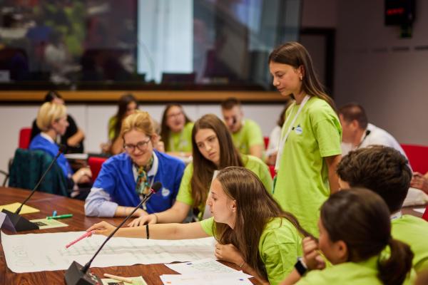 Young people working in groups and speaking into a microphone